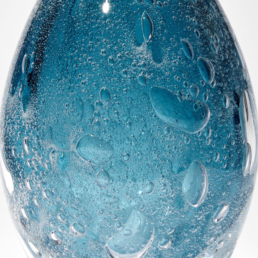 fading rich blue ovoid sculpture with internal bubbles hand made from glass