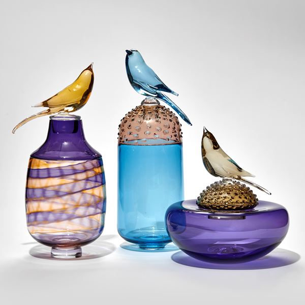 purple and bronze jar with swirling pattern and stopped with perched bird hand made from glass