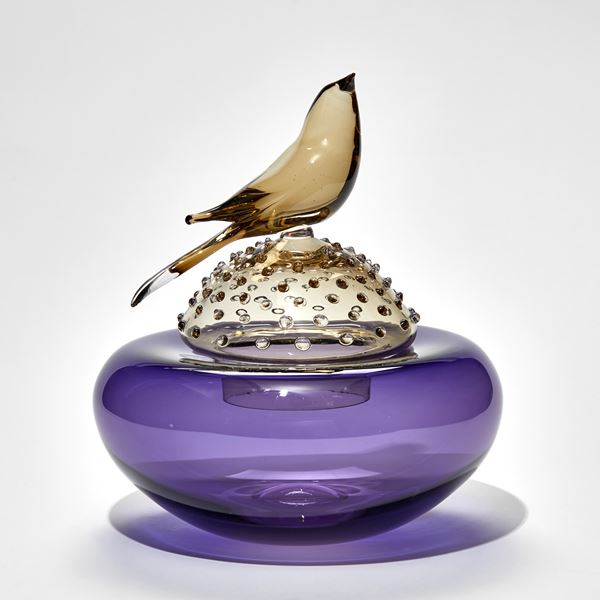 purple and bronze round lidded domed jar with bird perched on the top hand made from glass