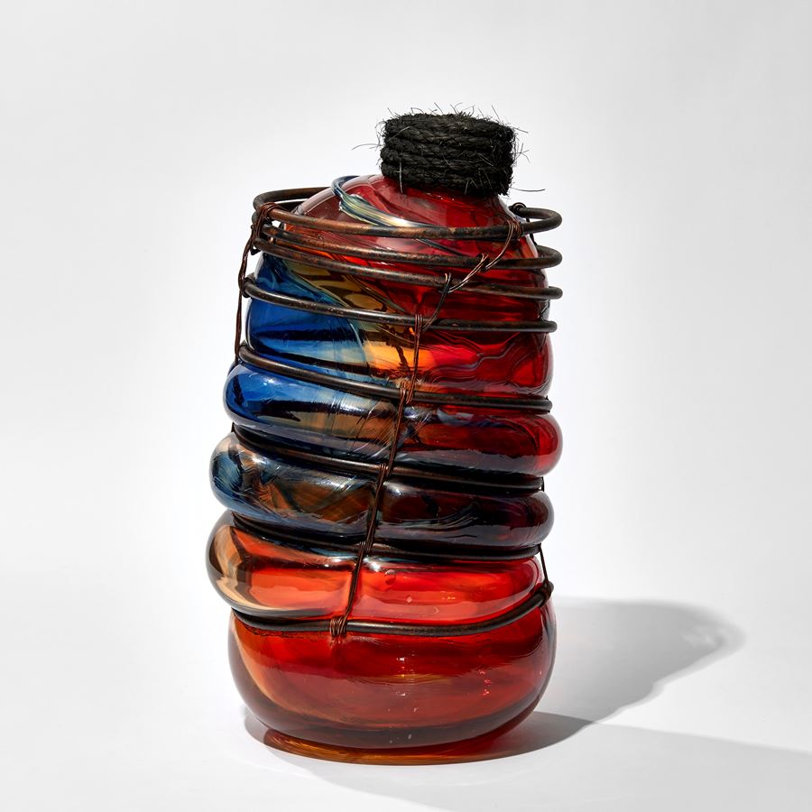 red and blue glass jar bound in a aged copper cage with rope stopper