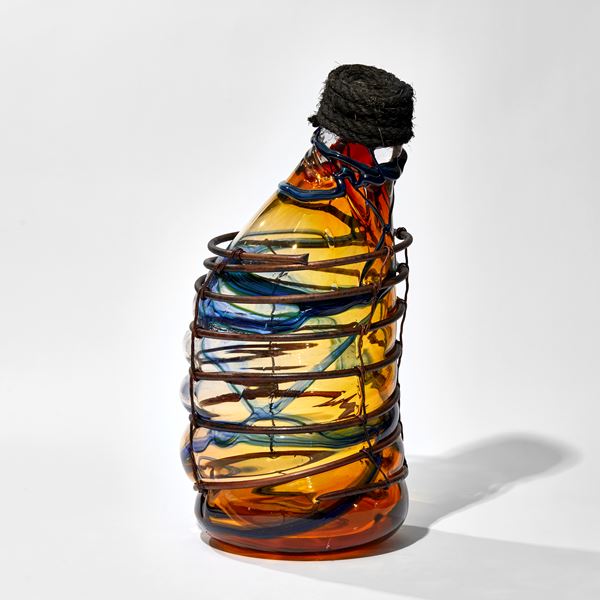 red amber and blue lopsided long necked bottle blown in to a copper cage with rope stopper hand made from glass