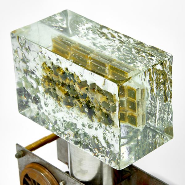 chunky ages metal train chassis with solid rectangular mass of glass above with inner winking eyes handmade from glass 