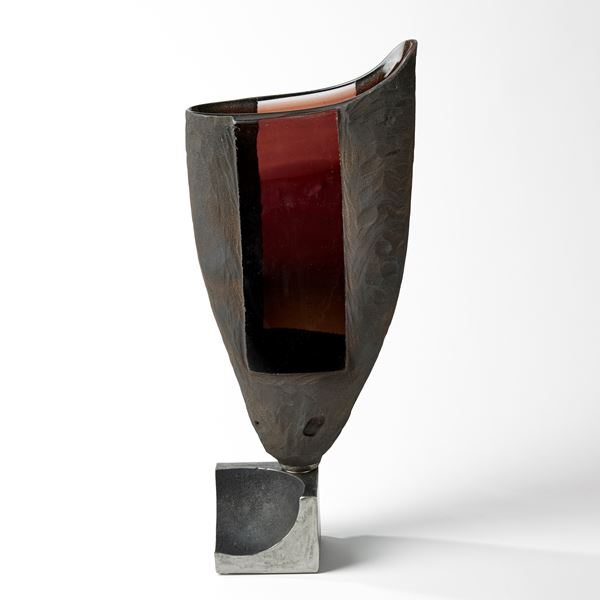 amber vessel with raised fin perched on a steel base hand made from glass