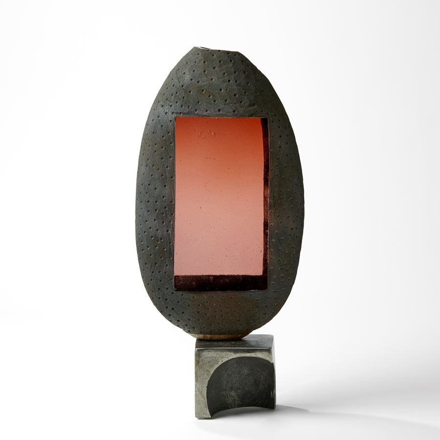 aged grey and brown ovoid glass sculpture with peach transparent rectangular windows and steel base