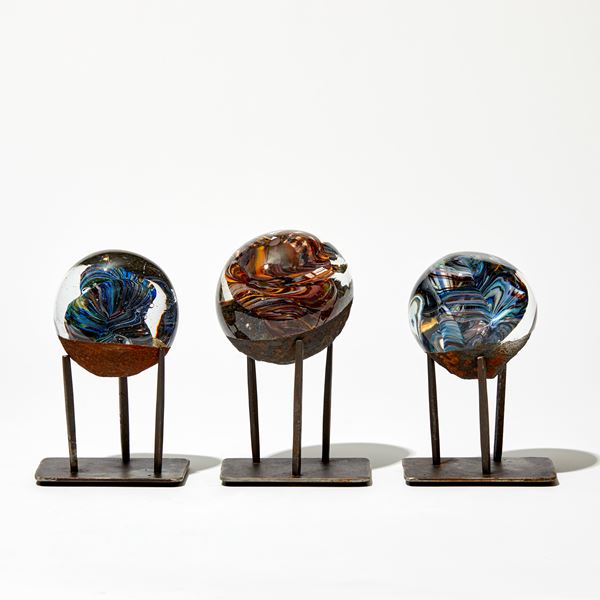 marble like round glass sculpture in clear blue and rust brown on three pronged steel base