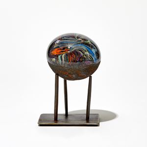 round sculpture perched on a three pronged steel base handmade from glass with multicoloured interior