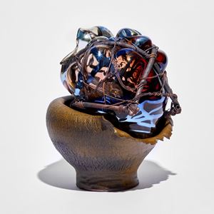 rich down wrinkled bowl with leathery appearance cradling a mass of pink and blue glass bound in copper