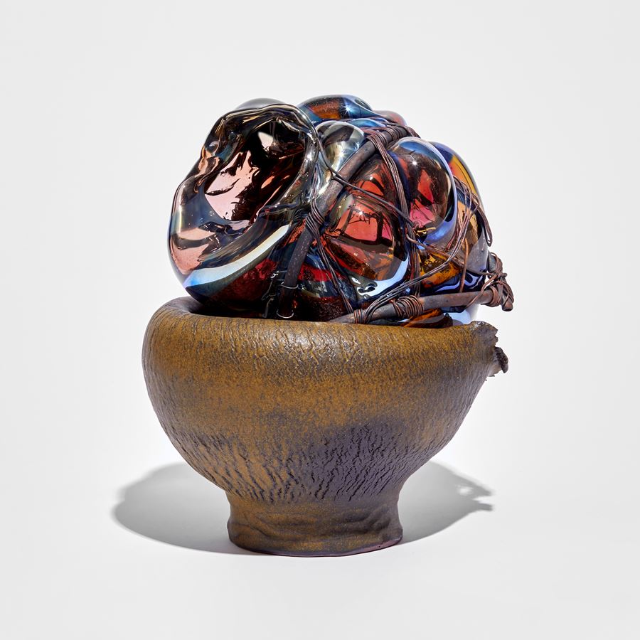rich down wrinkled bowl with leathery appearance cradling a mass of pink and blue glass bound in copper
