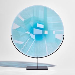turquoise and blue etched glass plate with raised graphic abstract pattern on a black metal base