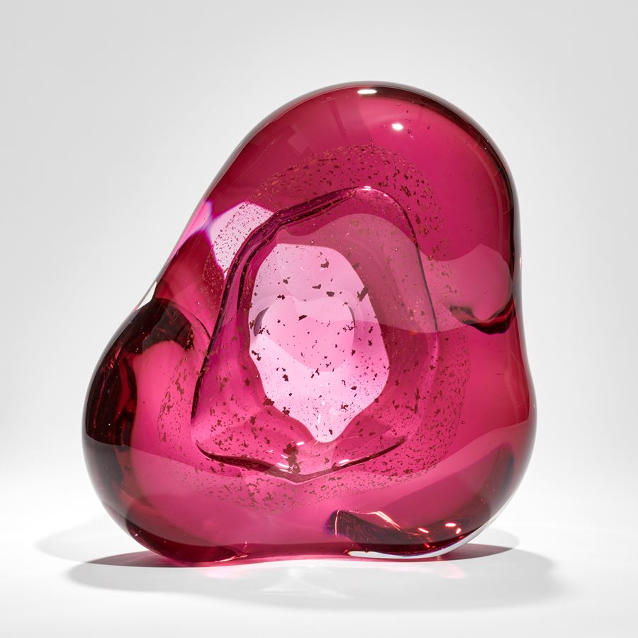 blobby pink mass of glass with central hole and swirling mass of trapped small fragments of glass