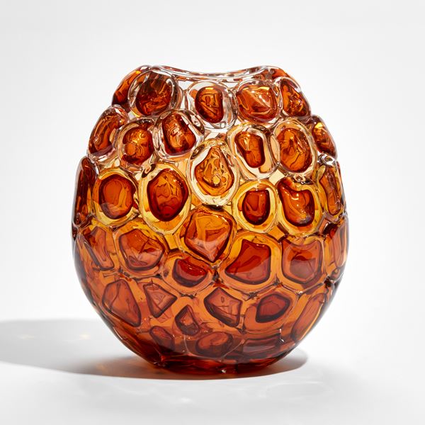 oval glass vase in amber and dark orange with the appearance as if created from stacked oversized bubbles