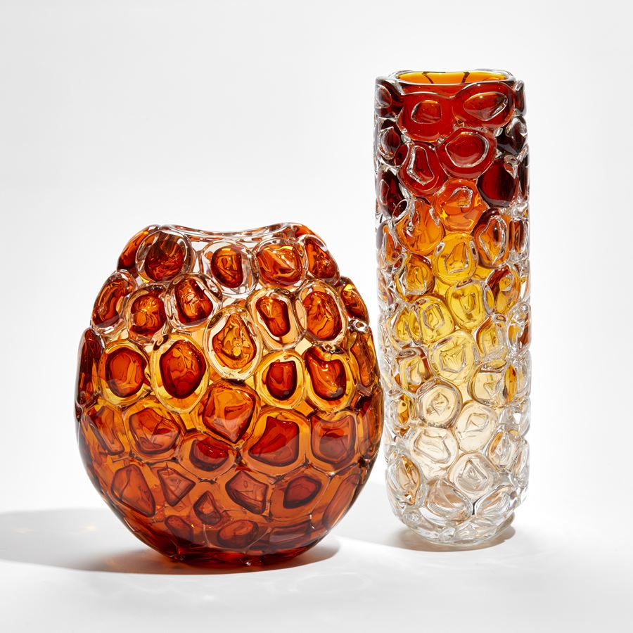 oval glass vase in amber and dark orange with the appearance as if created from stacked oversized bubbles