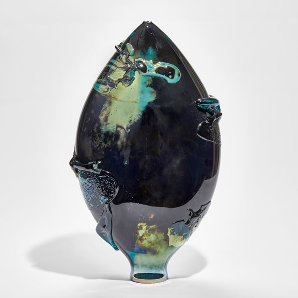 black blue and green lustrous oval vessel with organic smeared texture across the surface handmade from glass