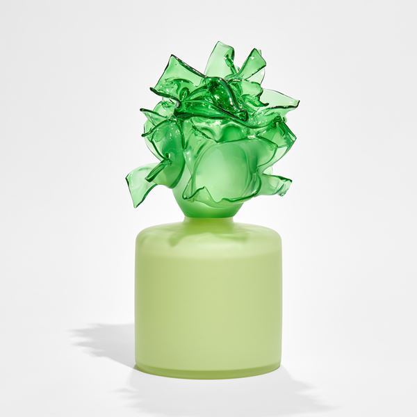 round soft green box with bright green abstract floral adornment on the top hand made from glass 