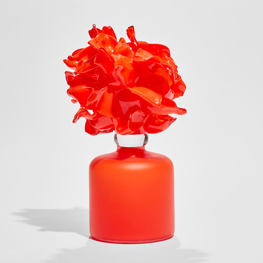 bright orange frosted rounded base with bursting abstract floral mass on top hand made from glass