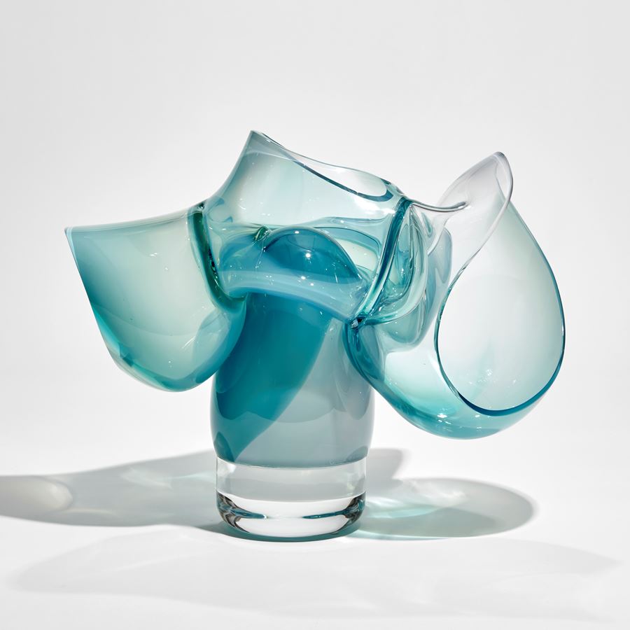 abstract sculpture of soft tubular bubbles in transparent clear and turquoise glass held aloft on a central solid trunk hand made from glass