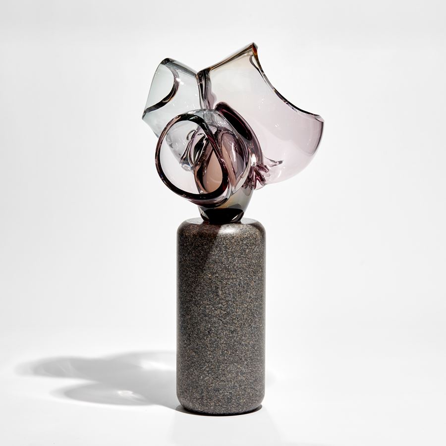 abstract floral sculpture with column of dark grey stone base with transparent purple pink cut bubbles on top