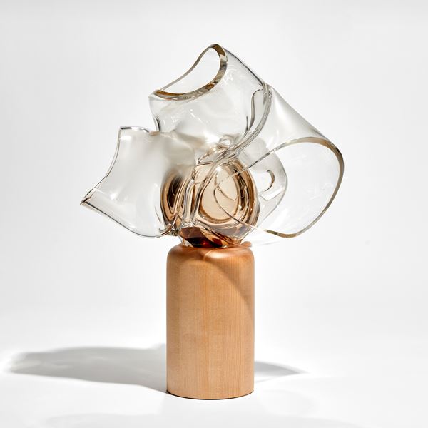 abstract human heart sculpture perched on a column of birch wood hand made from bronze tinted glass