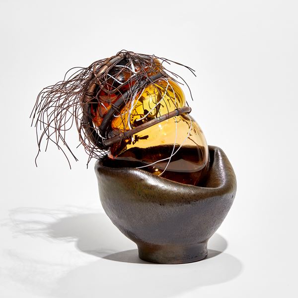khaki coloured ceramic base with amber amorphous shaped glass section bound in copper tube with copper wire hair
