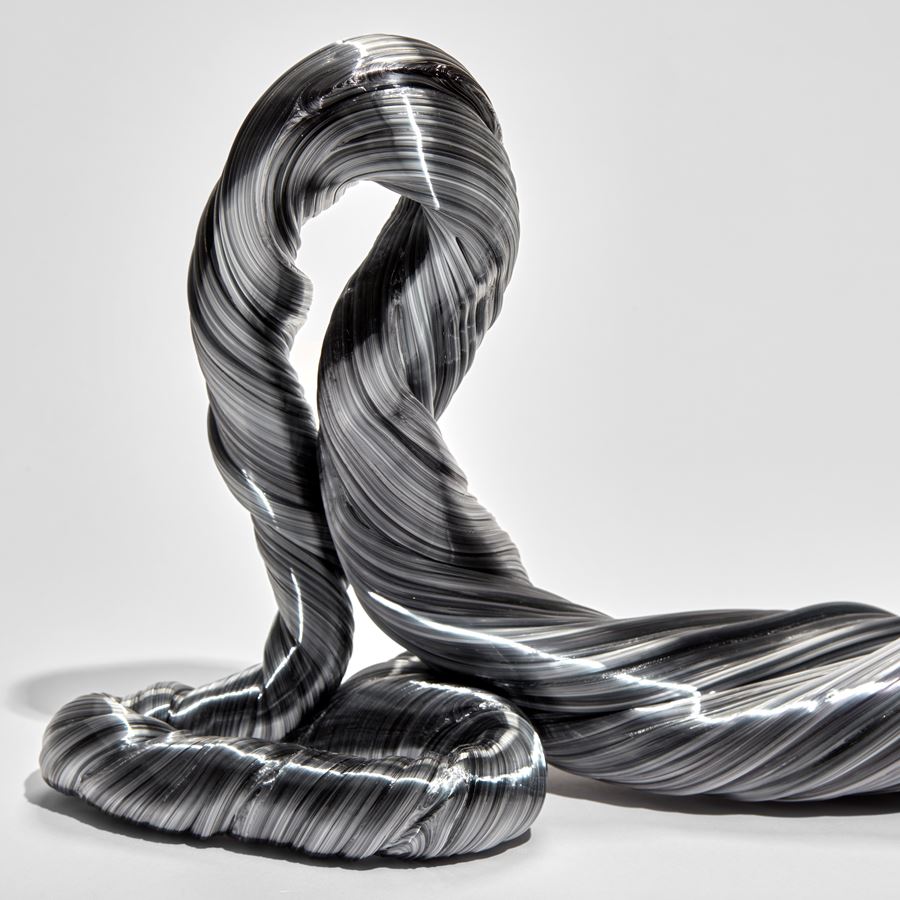 grey twisted and looping ridged sculpture mimicking an unravelling piece of wool hand made from glass