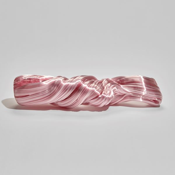 ridged and undulating pink twisted long glass sculpture with the appearance as if made from pulled and stretched sugar cane