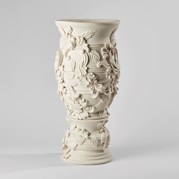 flared tall column shaped vase with banded ridges covered in organic swirls and floral motifs handmade from porcelain