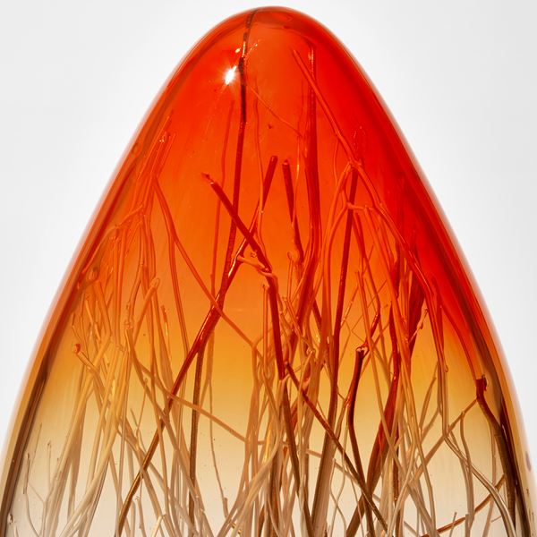 tall long ovoid sculpture with pointed top in bright orange fading to clear then white with interior filled with thin canes in white and gold hand made from glass