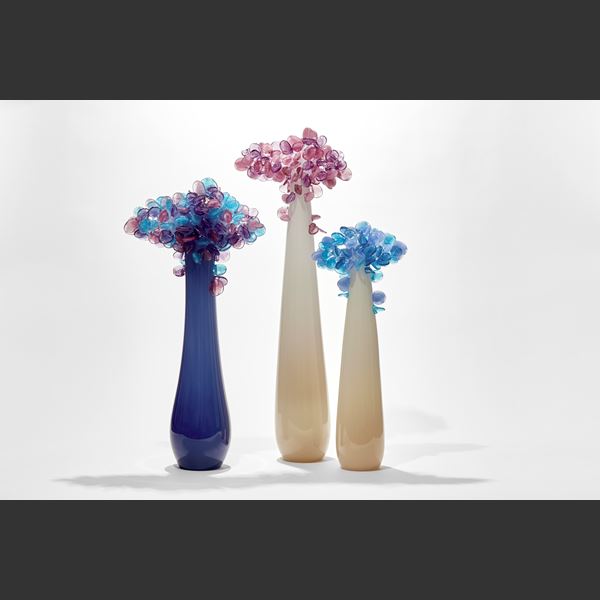 simplified tree with elongated tear shaped smooth trunk in dark blue lightening to the top with a cluster of lollipop leaves on top in blue and lilac handmade from glass