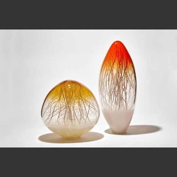 tall long ovoid sculpture with pointed top in bright orange fading to clear then white with interior filled with thin canes in white and gold hand made from glass