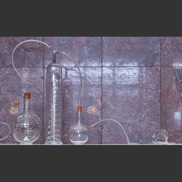 sculptural installation with scientific bottles connected by tubes with rubber bungs hand made from glass some with colour some in just clear