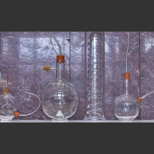 sculptural installation with scientific bottles connected by tubes with rubber bungs hand made from glass some with colour some in just clear