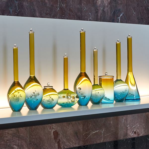 set of nine scientific looking bottles all different shapes fading from aqua at the bottom to gold yellow at the top hand made from glass