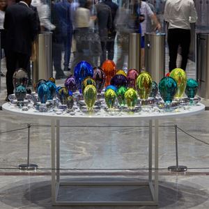 an installation consisting of a multitude of coloured droplets with a clear base each one a different colour creating a rainbow of hues handmade from glass