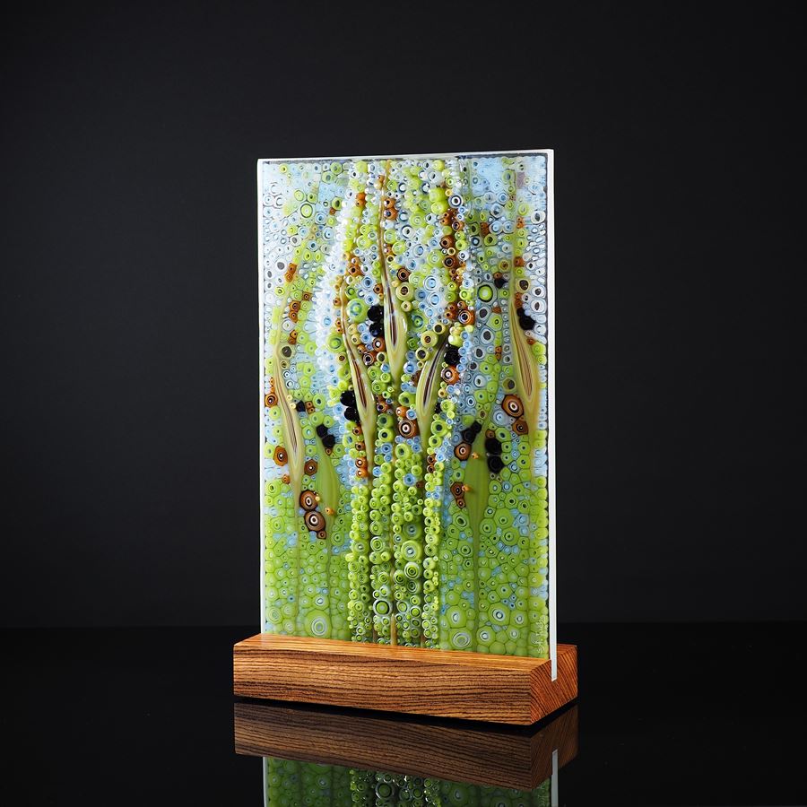 rectangular panel with bubbles and grass seed shapes in aqua blue green and deep red hand made from glass with a zebrano wood base