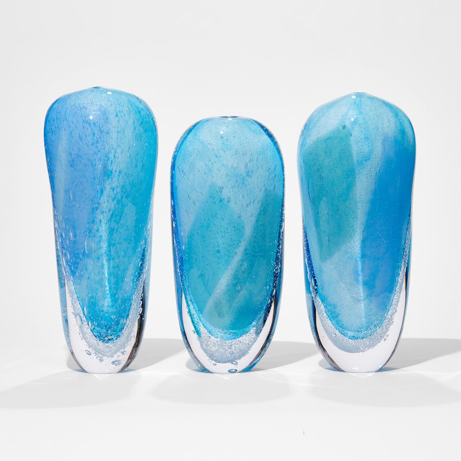 aqua light blue and clear tall soft forms based on icebergs with clear bottom lined with bubbles hand made from glass