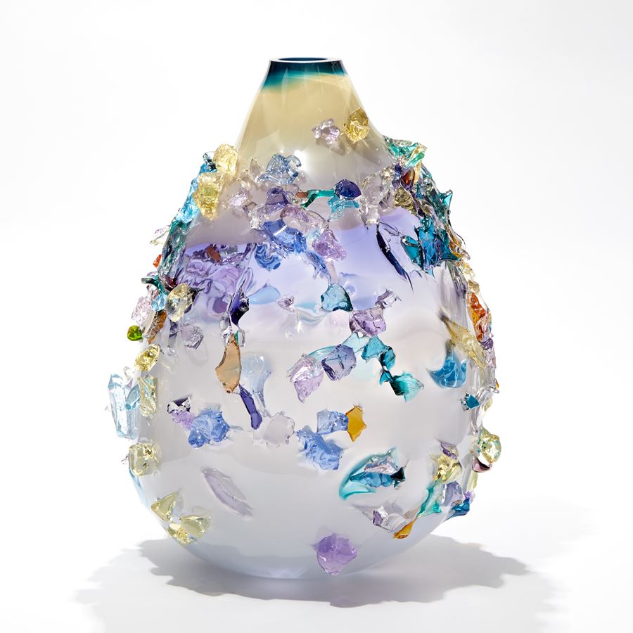 teardrop shaped vase in soft pale blue merging to purple and ochre covered in soft organic shards in aquas blues yellows and lilac hand made from glass