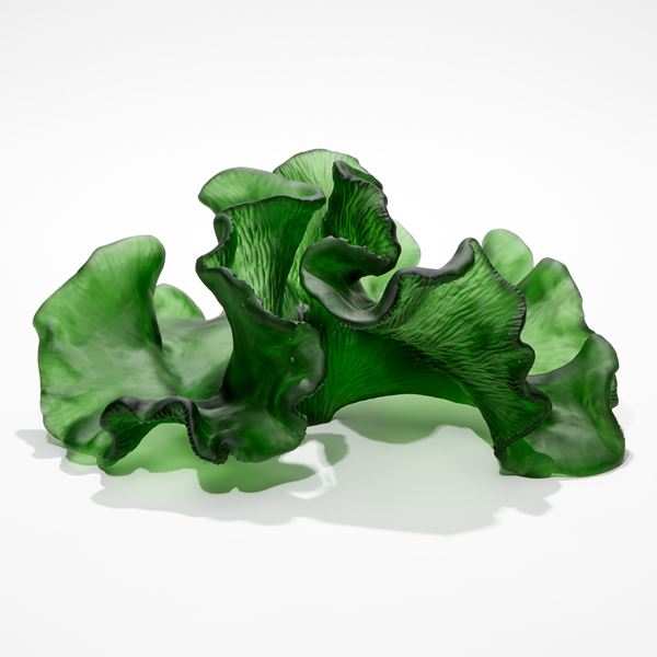 rich green sculpture resembling a piece of curling and frilled seaweed with soft matt surface one side with the other with ridged texture hand made from cast glass