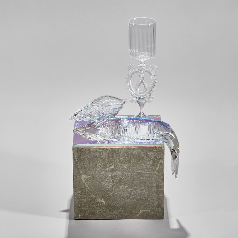 three dimensional still life with goblet shell and fish sitting on a grey concrete effect plinth handmade from glass