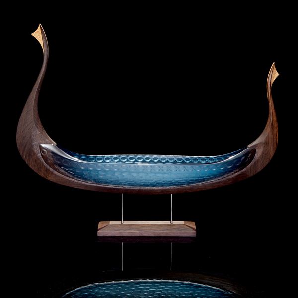 viking ship made from hand carved oak and handblown teal coloured glass with circular cutting detail raised up in a stand