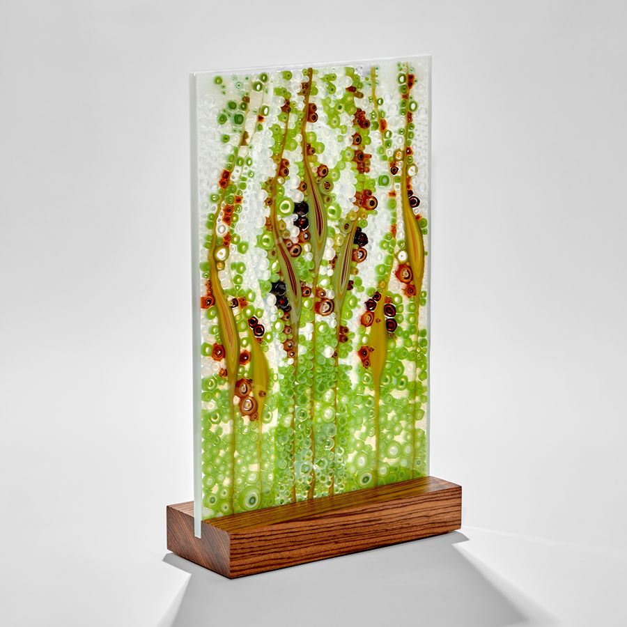 rectangular panel with bubbles and grass seed shapes in aqua blue green and deep red hand made from glass with a zebrano wood base