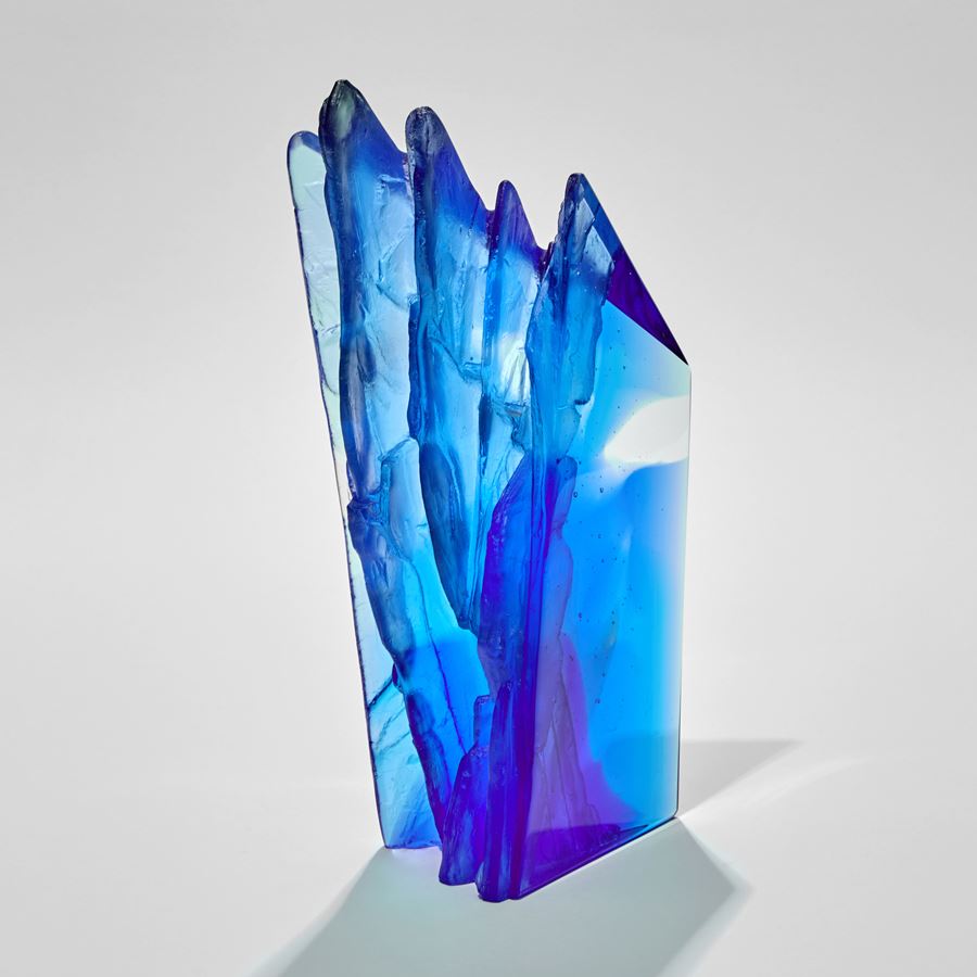 asymmetric mixed blues standing sculpture emulating a cliff face with two sides smooth and one ridged and textured hand made from glass