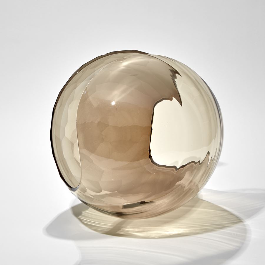 bronze transparent shell like sculpture with one side covered in facets hand made from glass