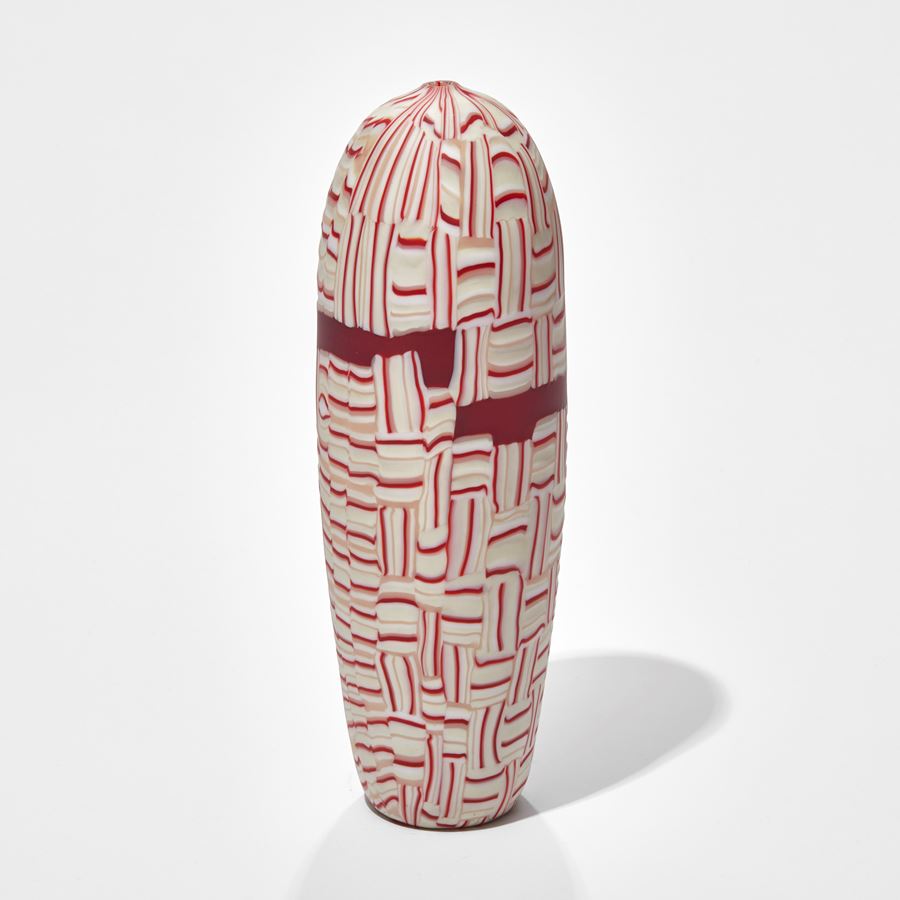 upright torpedo shaped vessel with abstract mosaic pattern in red white and pink hand made from glass