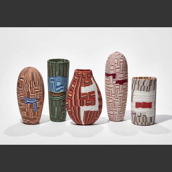 upright torpedo shaped vessel with abstract mosaic pattern in red white and pink hand made from glass