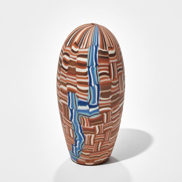 upright stumpy torpedo shaped glass sculpture with  abstract mosaic pattern in brown blue lack and white handmade from glass