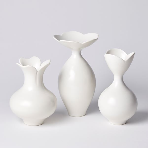 short white rounded vase with narrowing neck and flared opening branching in to three petals hand made from porcelain