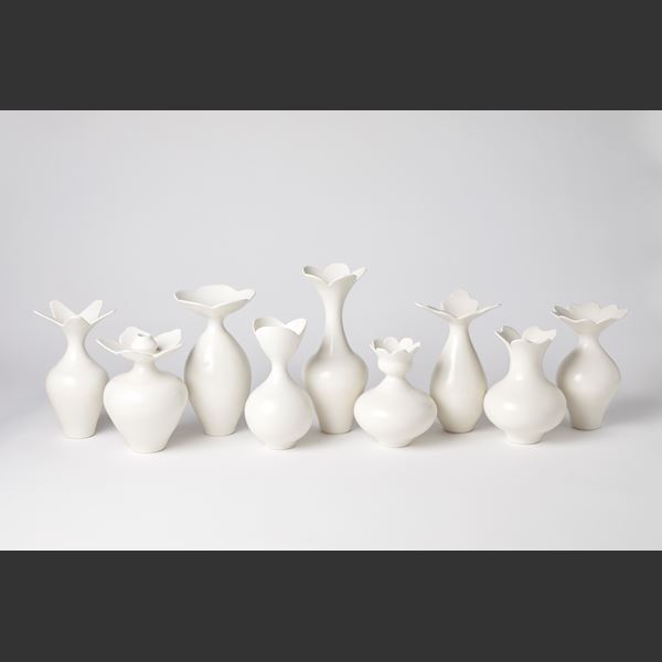 short white rounded vase with narrowing neck and flared opening branching in to three petals hand made from porcelain