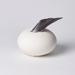 squat rounded white form with a black jagged edged shard piecing through the top hand made from porcelain