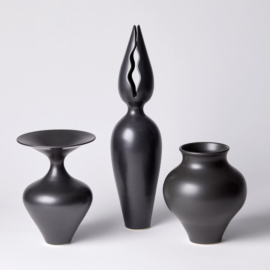 tall black porcelain sculpture with classical vase and pointed flower bud top with narrow wavy openings