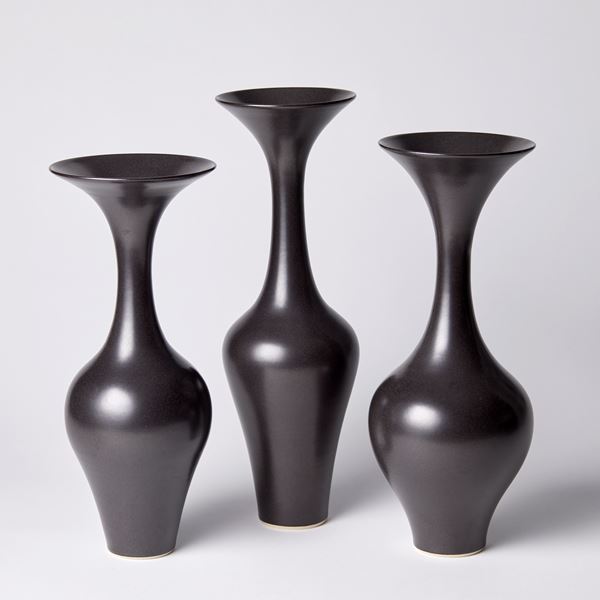 black classical shaped vase with long neck and flared rim hand thrown from porcelain and glazed a dark ebony brown